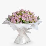Bouquet of pink roses wrapped in white paper on a white background