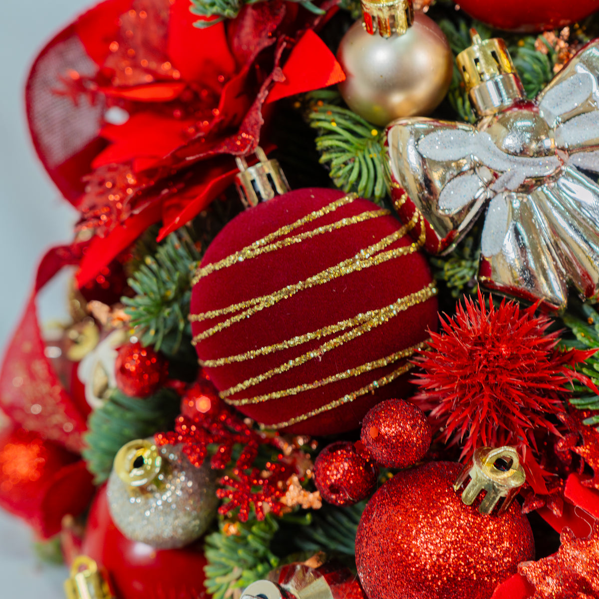 Close-up of a Christmas wreath with red and gold ornaments on a white background