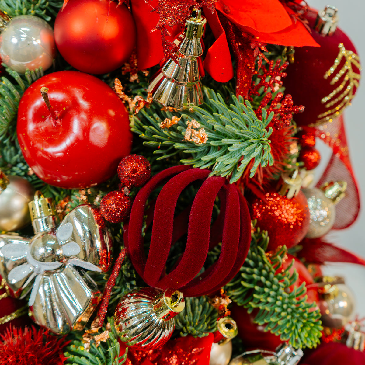 Close-up of a Christmas wreath with red and gold ornaments on a white background