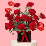 Bouquet of red roses with greenery on a pink background