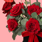Bouquet of red roses with green leaves on a pink background