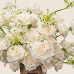 Bouquet of white and light pink roses with greenery on a neutral background