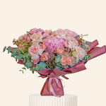 Bouquet of pink and white flowers wrapped in pink paper on a white background