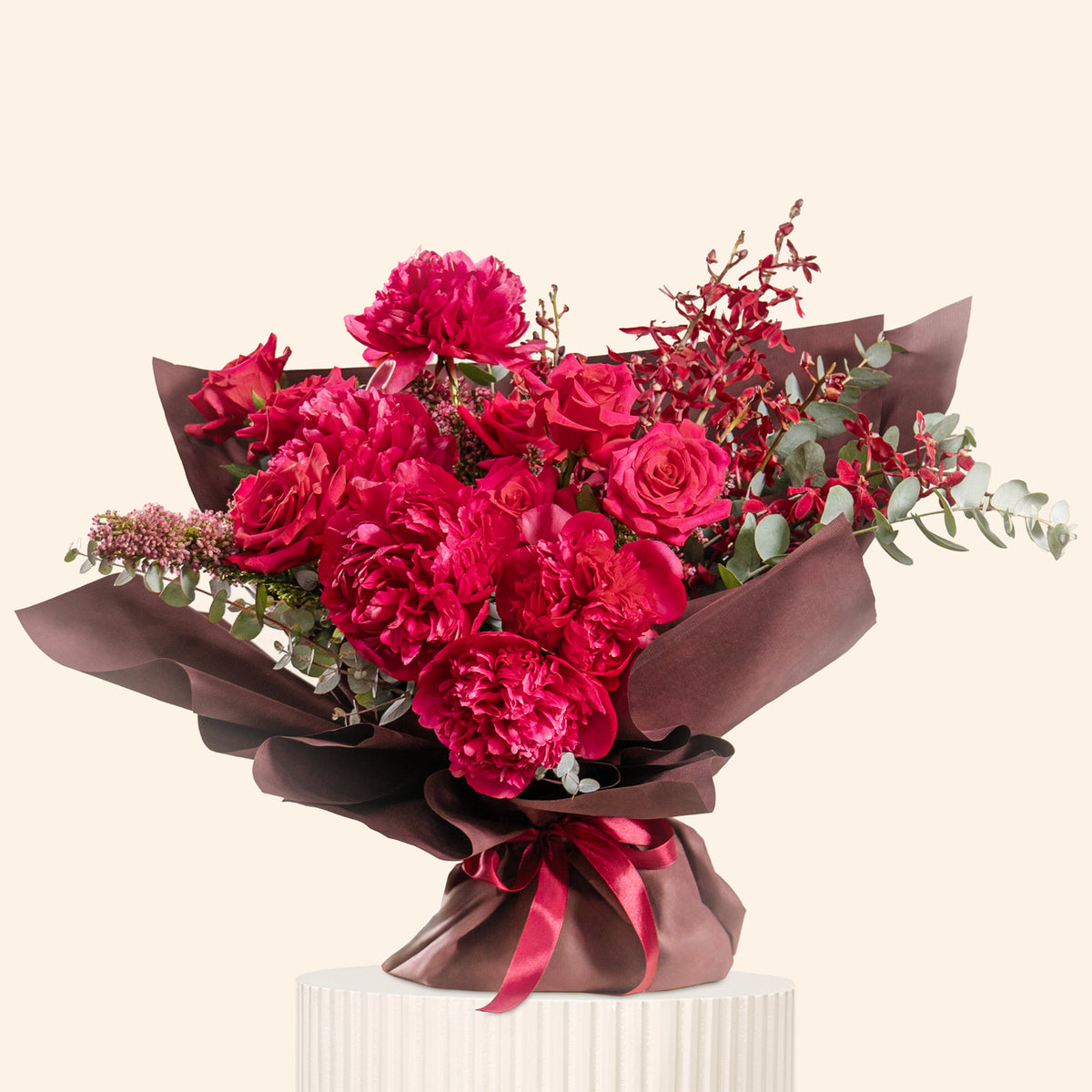 Bouquet of red flowers wrapped in brown paper with a ribbon on a beige background