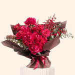 Bouquet of red flowers wrapped in brown paper with a ribbon on a beige background