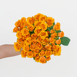Bouquet of yellow roses held by a person on a light gray background