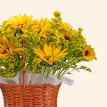 Bouquet of yellow sunflowers in a woven basket on a light beige background
