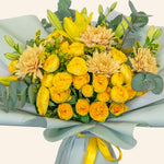 Bouquet of yellow and beige flowers with greenery on a light gray background