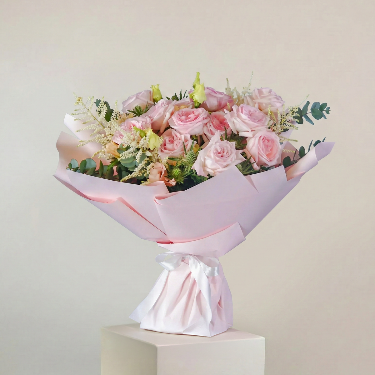 Bouquet of pink roses wrapped in white paper on a light gray background