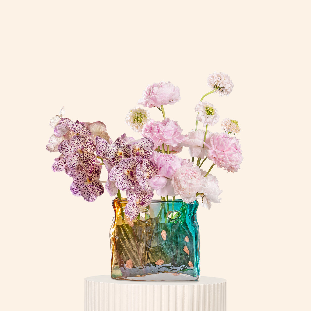 Decorative vase with pink flowers on a white pedestal against a light beige background