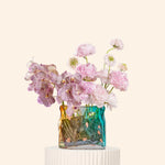 Decorative vase with pink flowers on a white pedestal against a light beige background