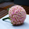 Bouquet of pink flowers on a white surface with a blurred wooden background