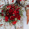 Bouquet of red roses held by a person with intricate henna designs on their hands.