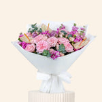 Bouquet of pink roses and hydrangeas with a white wrap on a beige background