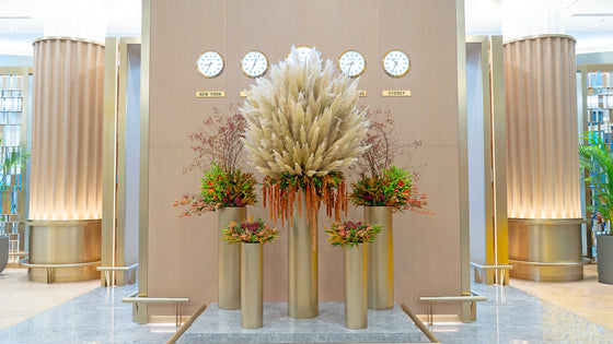 Luxury First Class Lounge floral installation featuring a grand pampas grass arrangement with autumnal foliage and cascading textures in gold pedestal vases, designed by Al Jowder Flowers Dubai.