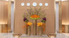 Large luxury floral installation with orange, green, and purple flowers arranged in tall gold vases under world clocks in a modern lobby.