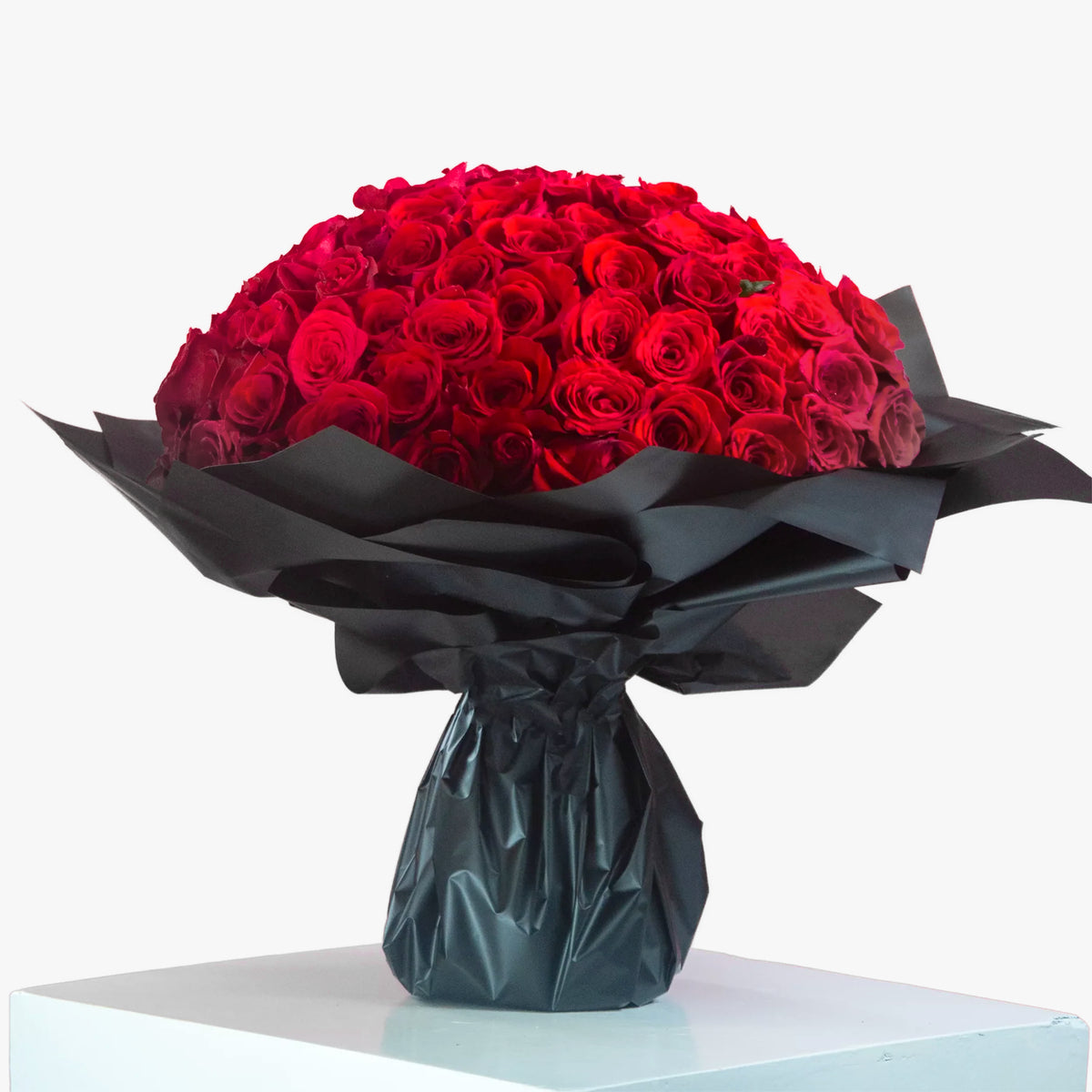 Bouquet of red roses wrapped in black paper on a white background