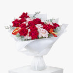 Bouquet of red and pink flowers wrapped in white paper on a white background