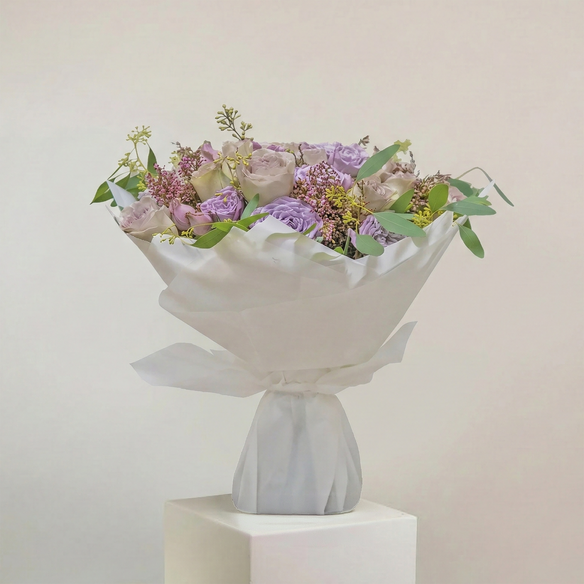 Bouquet of flowers in a white wrap on a light gray background