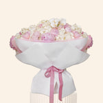 Bouquet of pink and white flowers wrapped in white paper with a pink ribbon on a light beige background