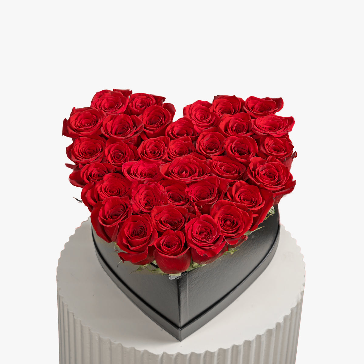 Heart-shaped arrangement of red roses in a box on a white background