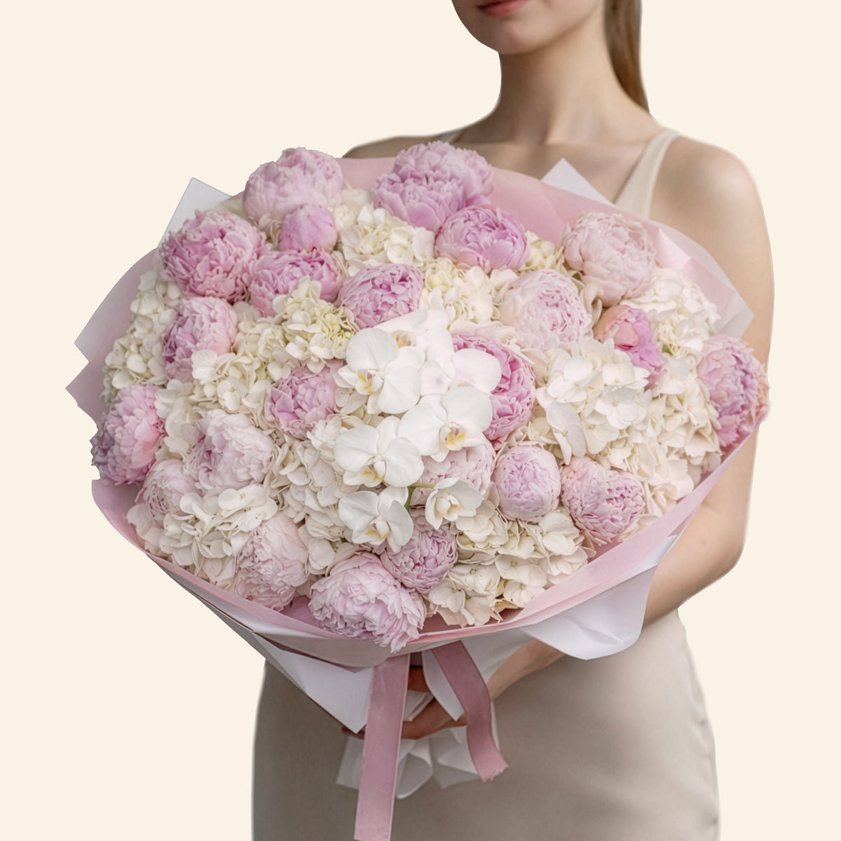 Bouquet of pink and white flowers held by a person against a beige background