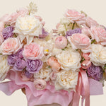 Bouquet of pink, white, and purple flowers with pink ribbons on a light background