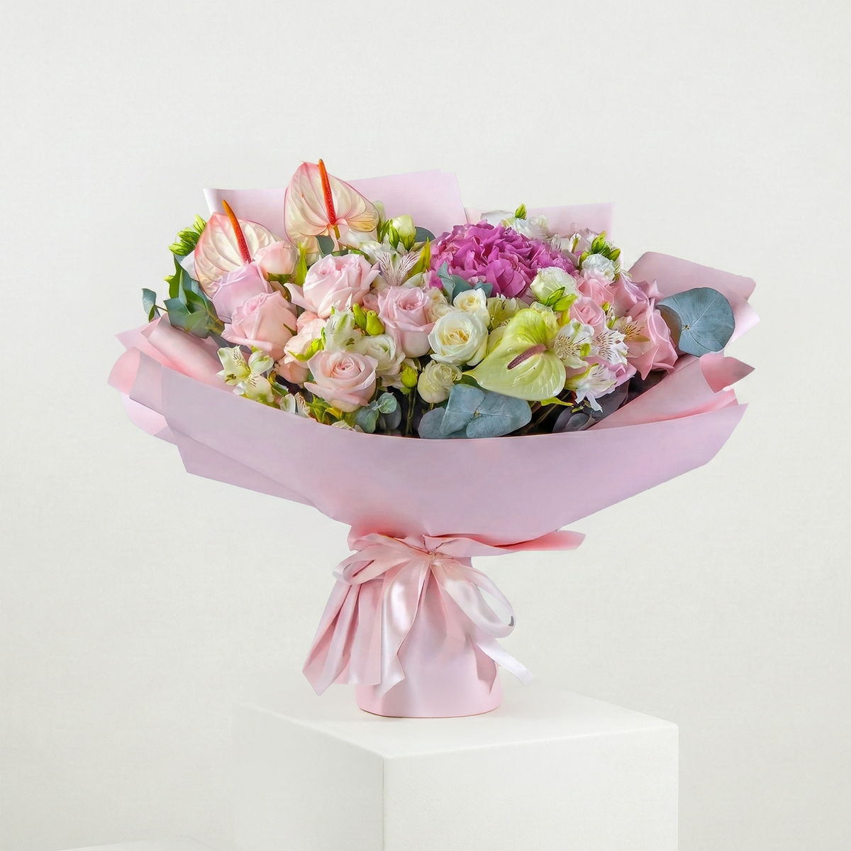 Bouquet of flowers wrapped in pink paper with a bow on a white background