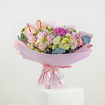 Bouquet of flowers wrapped in pink paper with a bow on a white background