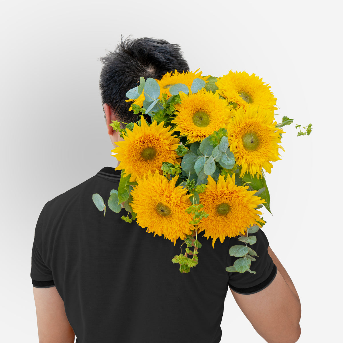 Person wearing a black shirt with yellow flowers and green leaves on a plain background