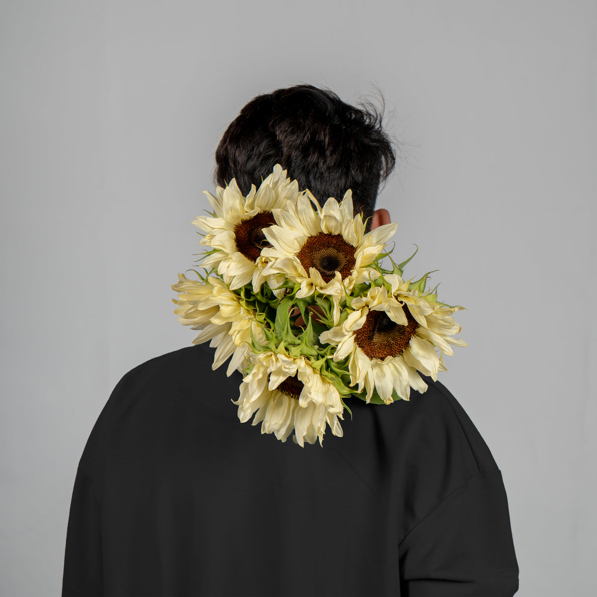 Person wearing a sunflower headband against a gray background