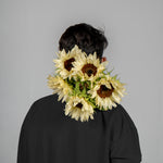 Person wearing a sunflower headband against a gray background