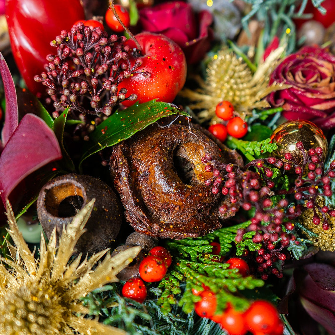 Close-up of a decorative arrangement with berries, flowers, and a chocolate donut.
