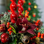 Decorative Christmas arrangement with red berries and greenery on a blurred festive background