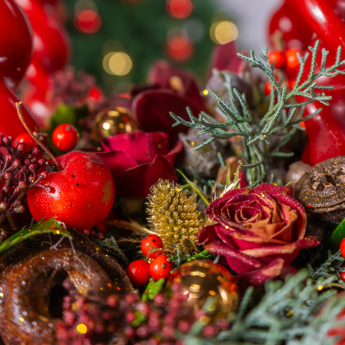 Close-up of festive decorations with red berries, gold balls, and greenery.