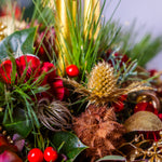 Decorative arrangement with red berries, green leaves, and gold elements on a blurred background