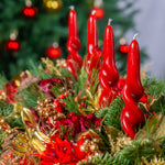 Decorative arrangement with red candles and greenery against a blurred festive background