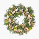 Decorative wreath with greenery, flowers, and ornaments on a white background