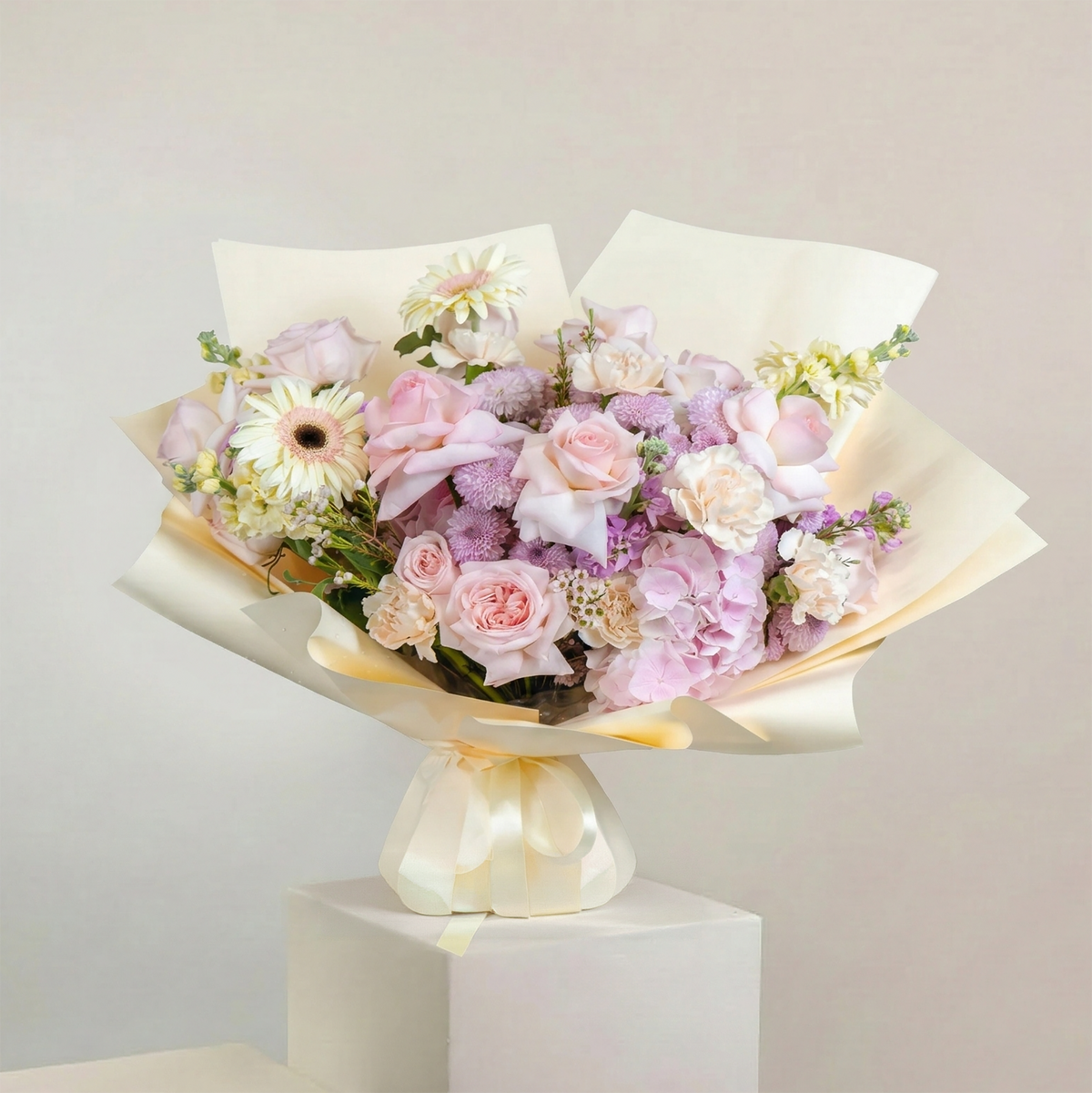 Bouquet of flowers wrapped in paper on a white pedestal against a light gray background