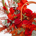 Basket filled with red roses and greenery on a white background