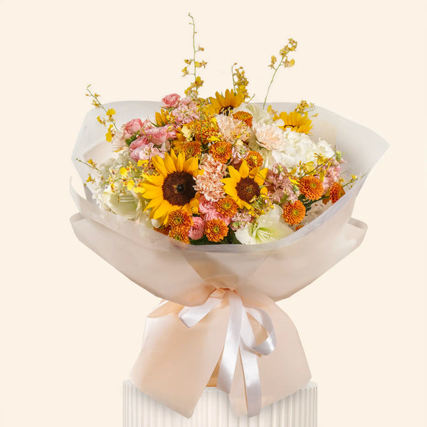 Bouquet of flowers with sunflowers and other varieties wrapped in white paper and ribbon on a white background