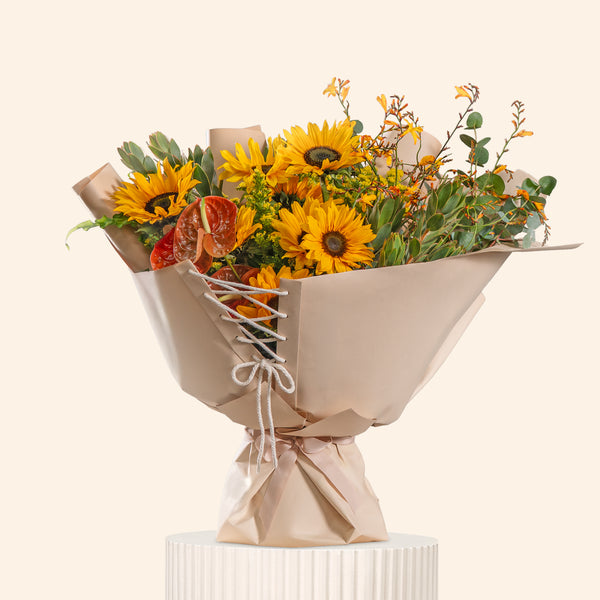 Bouquet of sunflowers and greenery wrapped in brown paper on a white background