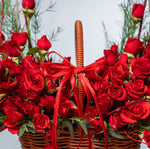 Basket of red roses with a red ribbon against a blurred natural background