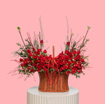 Basket of red roses with greenery on a pink background
