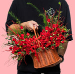 Person holding a basket of red roses against a pink background