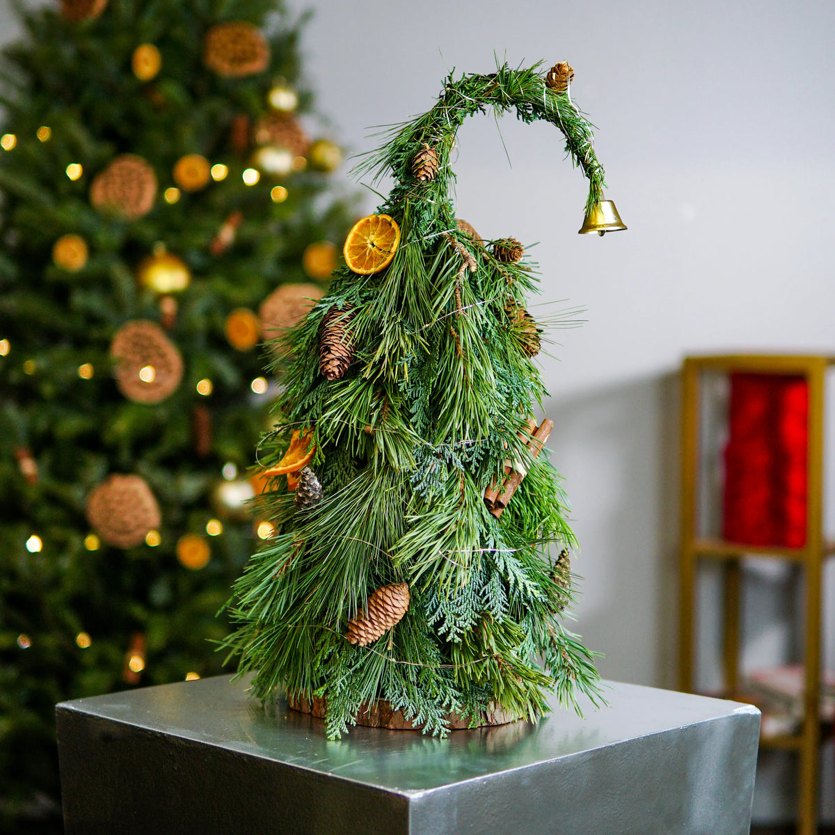 Decorative Christmas tree made of greenery on a stand with a blurred background