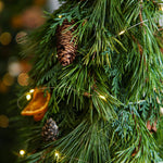 Close-up of a Christmas tree with pine cones and lights, blurred lights in the background