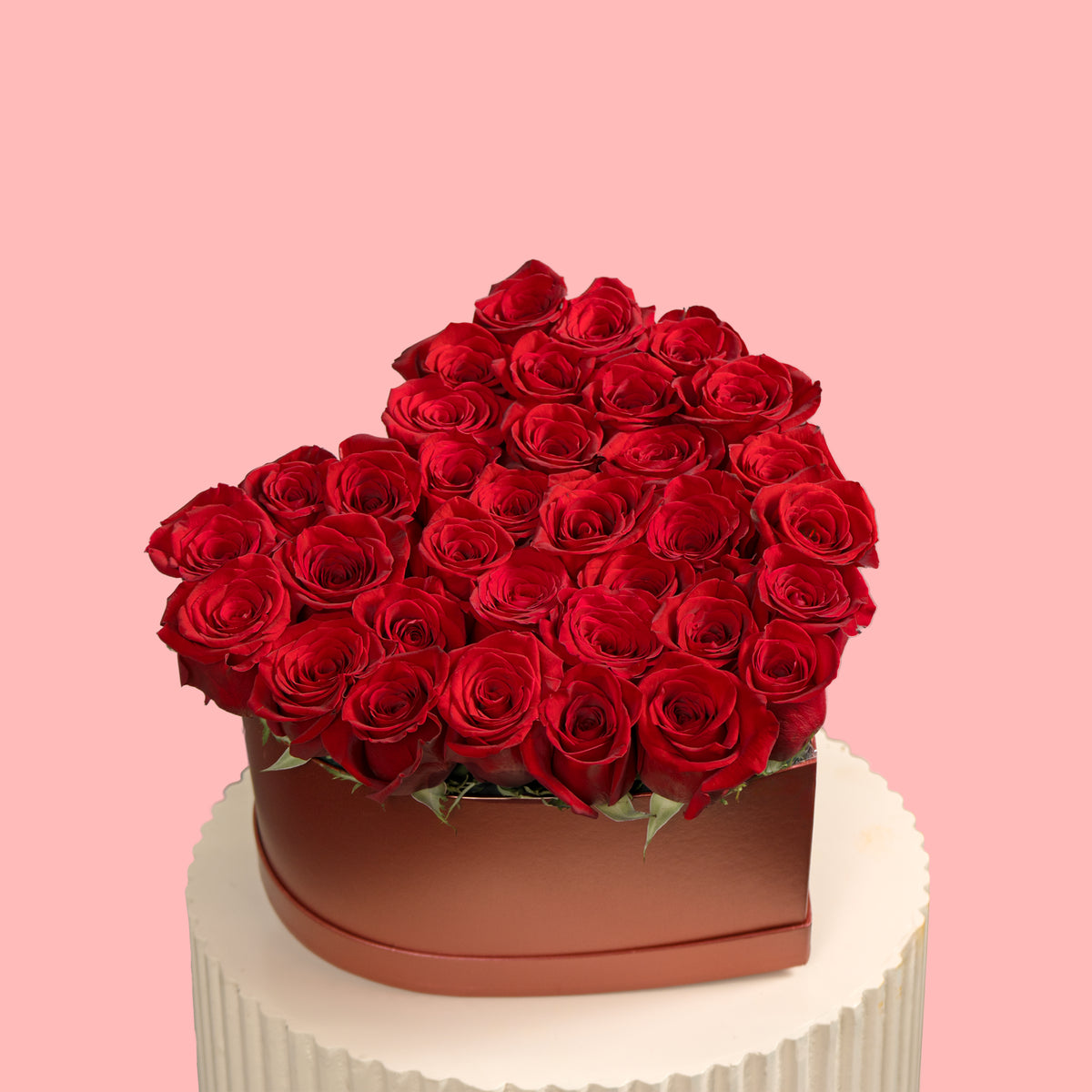 Heart-shaped box of red roses on a pink background