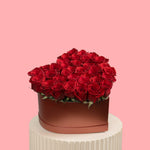 Heart-shaped box of red roses on a pink background