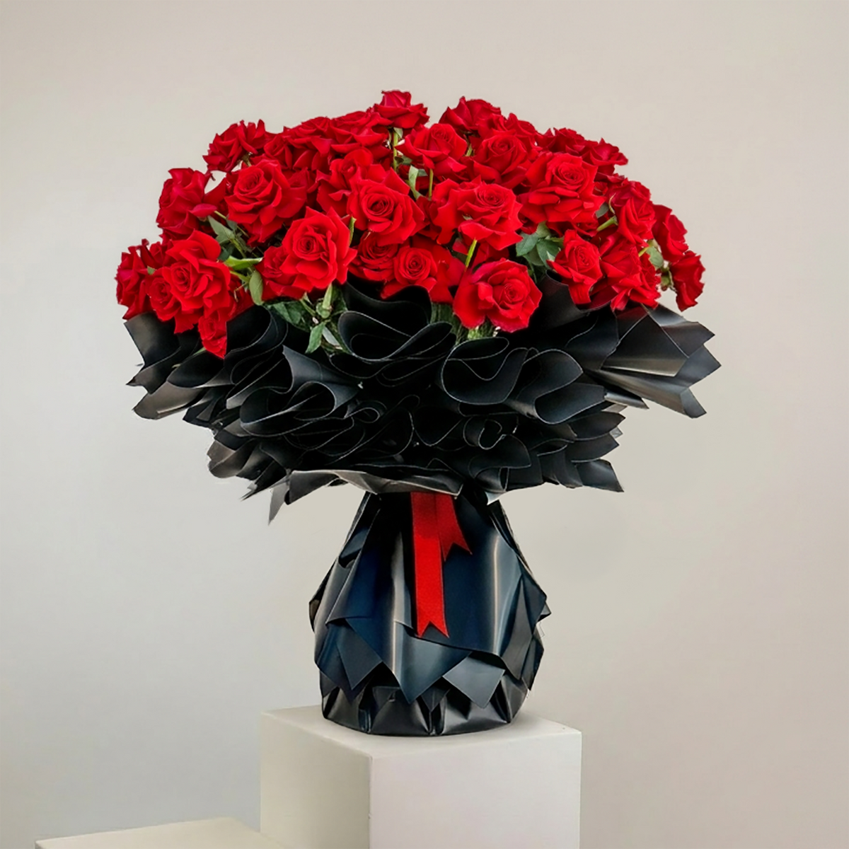 Bouquet of red roses in a black origami-style vase on a light gray background